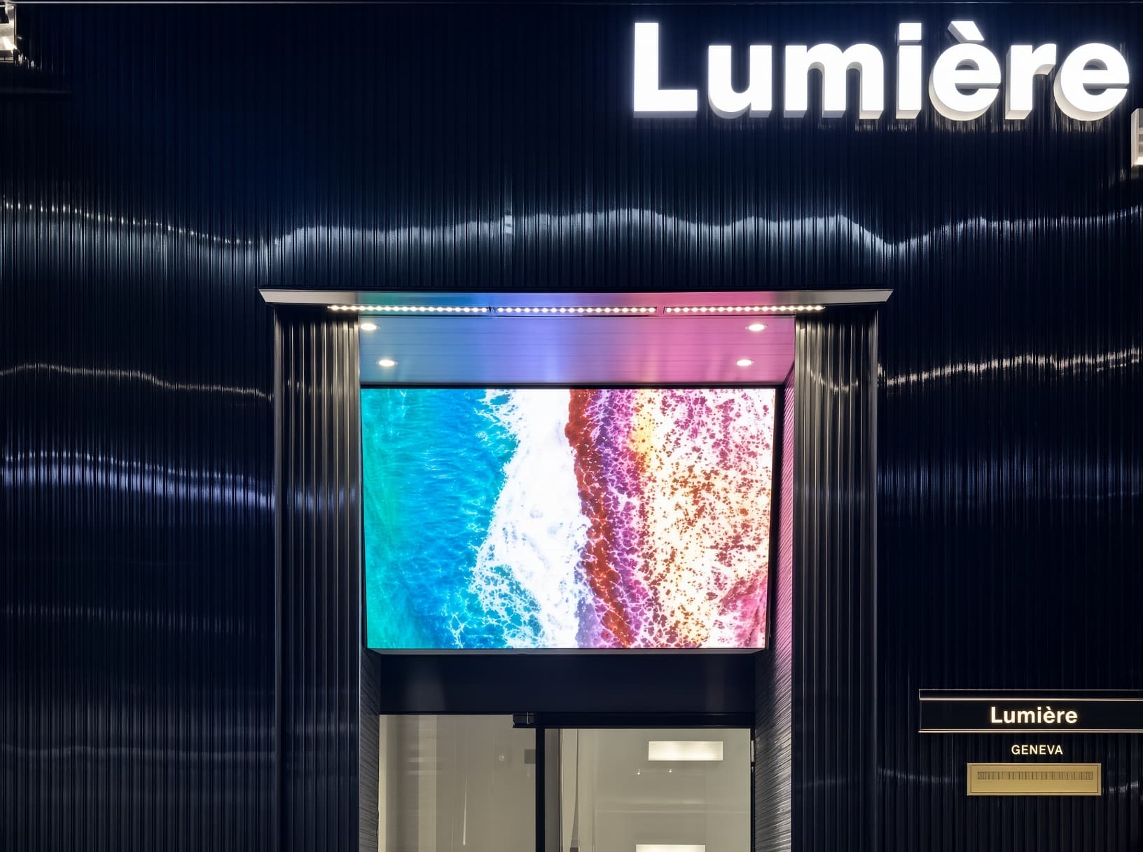 カンナム・リュミエール (강남 루미에르) · Lumièreの看板の下に、黒い外壁、海辺の映像の画面、入口が見えます。