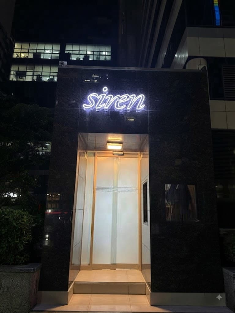 カンナム・セイレーン (강남 세이렌) · Sirenの光る看板と、黒い外壁に囲まれた明るい入口が写っています。