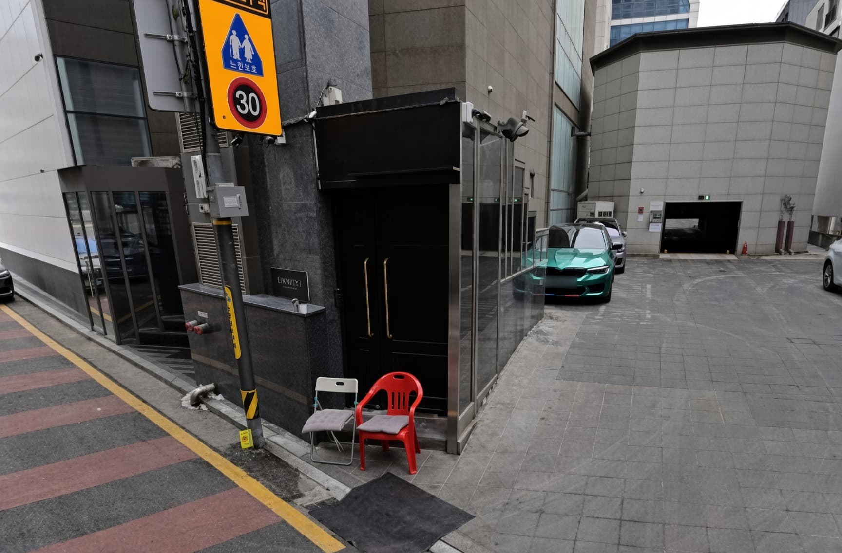 カンナム・トリニティ (강남 트리니티) · 建物前の黒い入口の構造物と、横の車両通路が見えます。