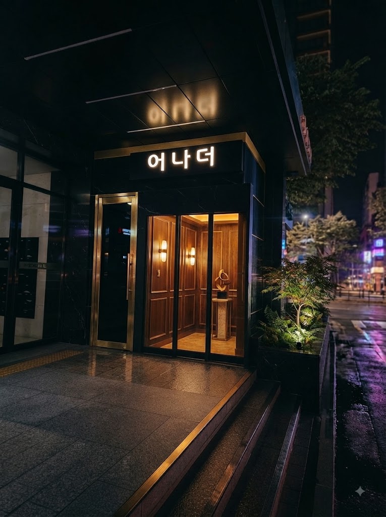 강남어나더 · 어나더 간판 아래 금빛 문틀과 출입구 앞 계단이 보입니다.