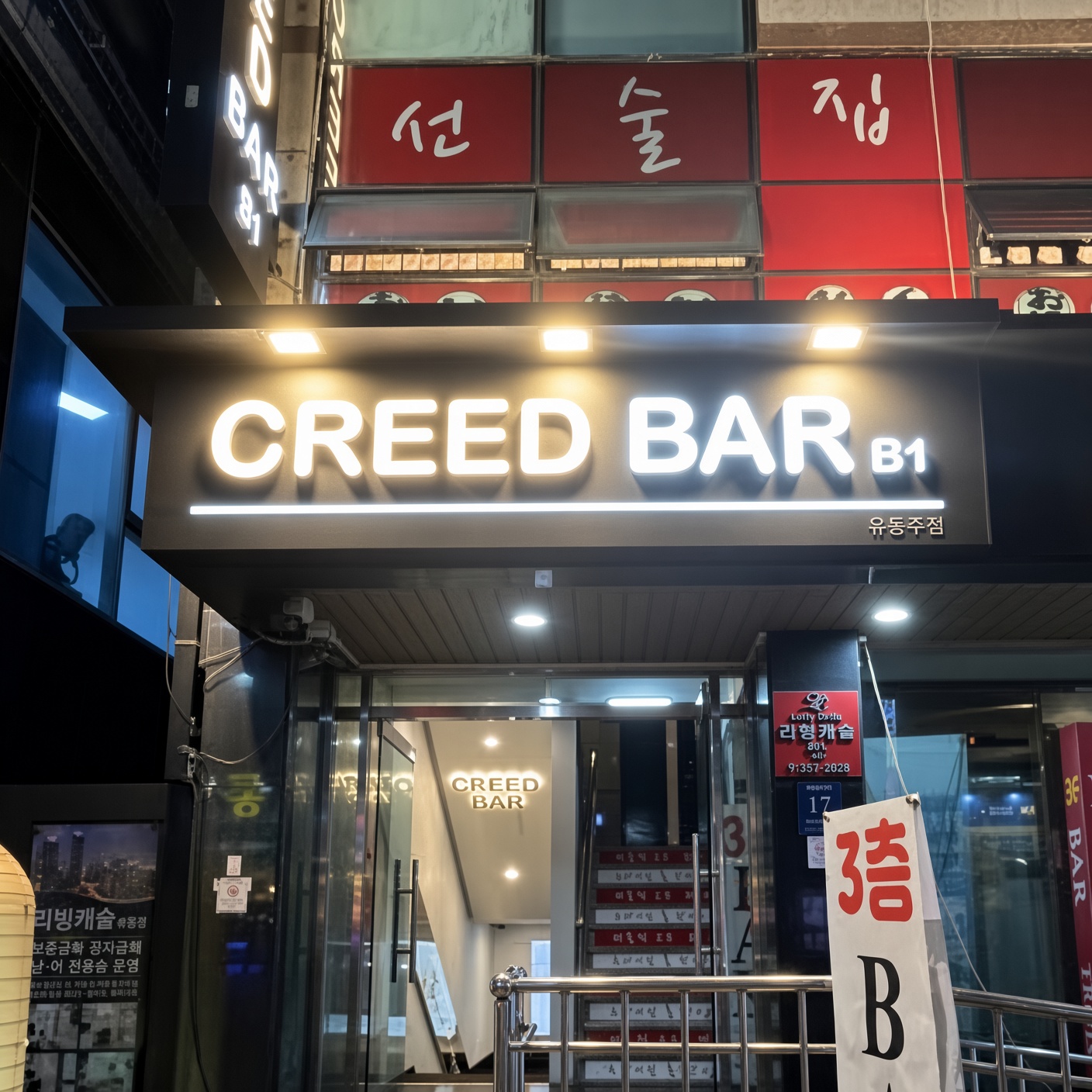 강남 크리드 · CREED BAR 간판 아래 유리 출입구와 양옆의 작은 간판들이 보입니다.