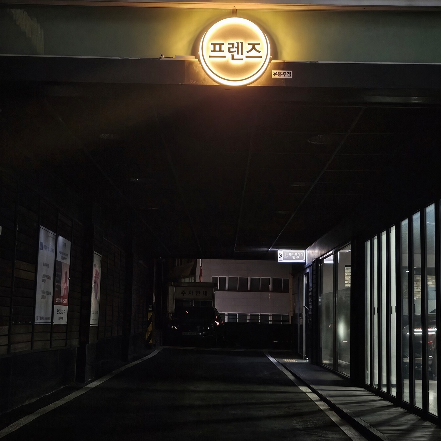 강남 프렌즈 · 둥근 프렌즈 간판 아래 길게 이어지는 어두운 통로와 옆 유리 벽이 보입니다.