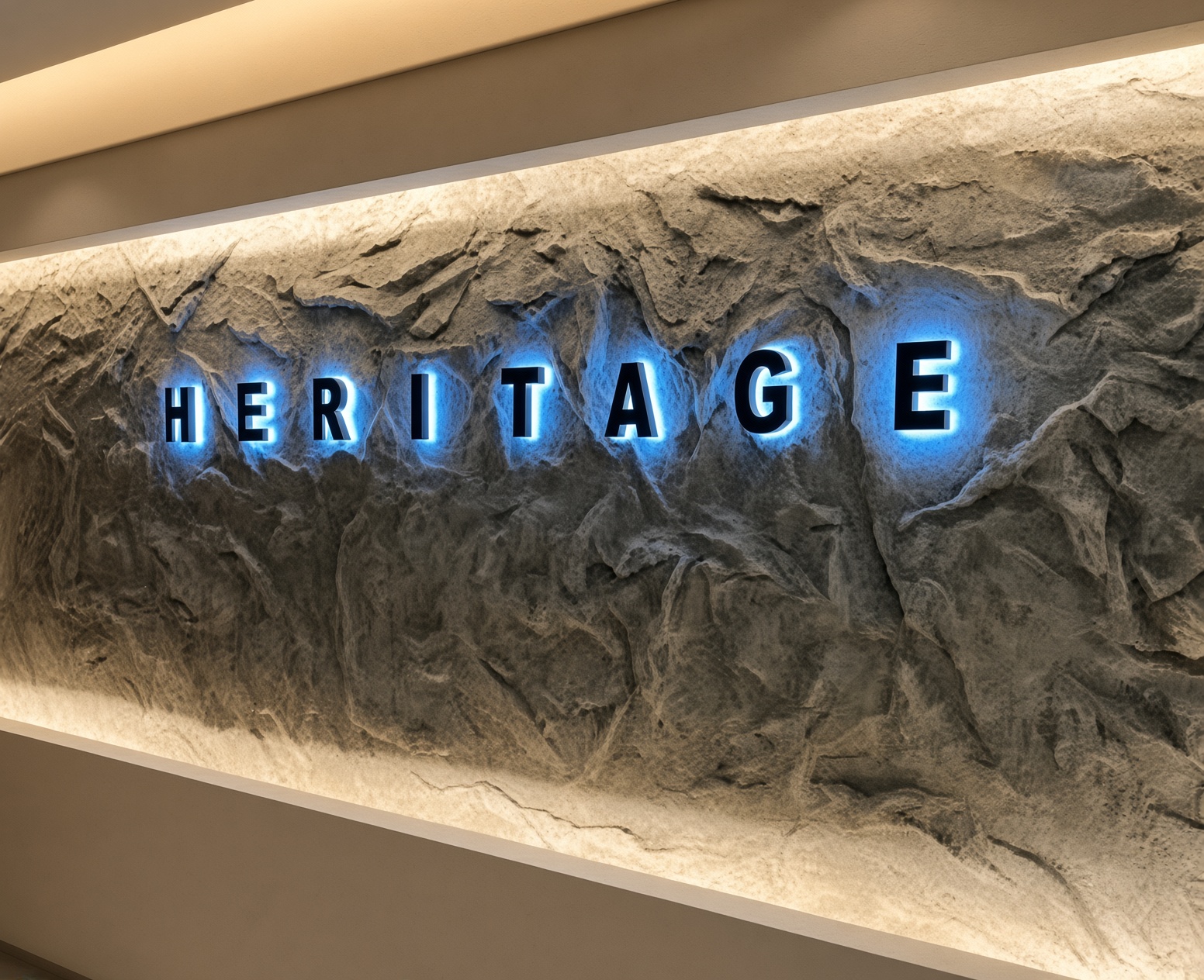 강남 헤리티지 · 거친 돌 질감의 벽면에 푸른빛 HERITAGE 글자와 간접 조명이 보입니다.