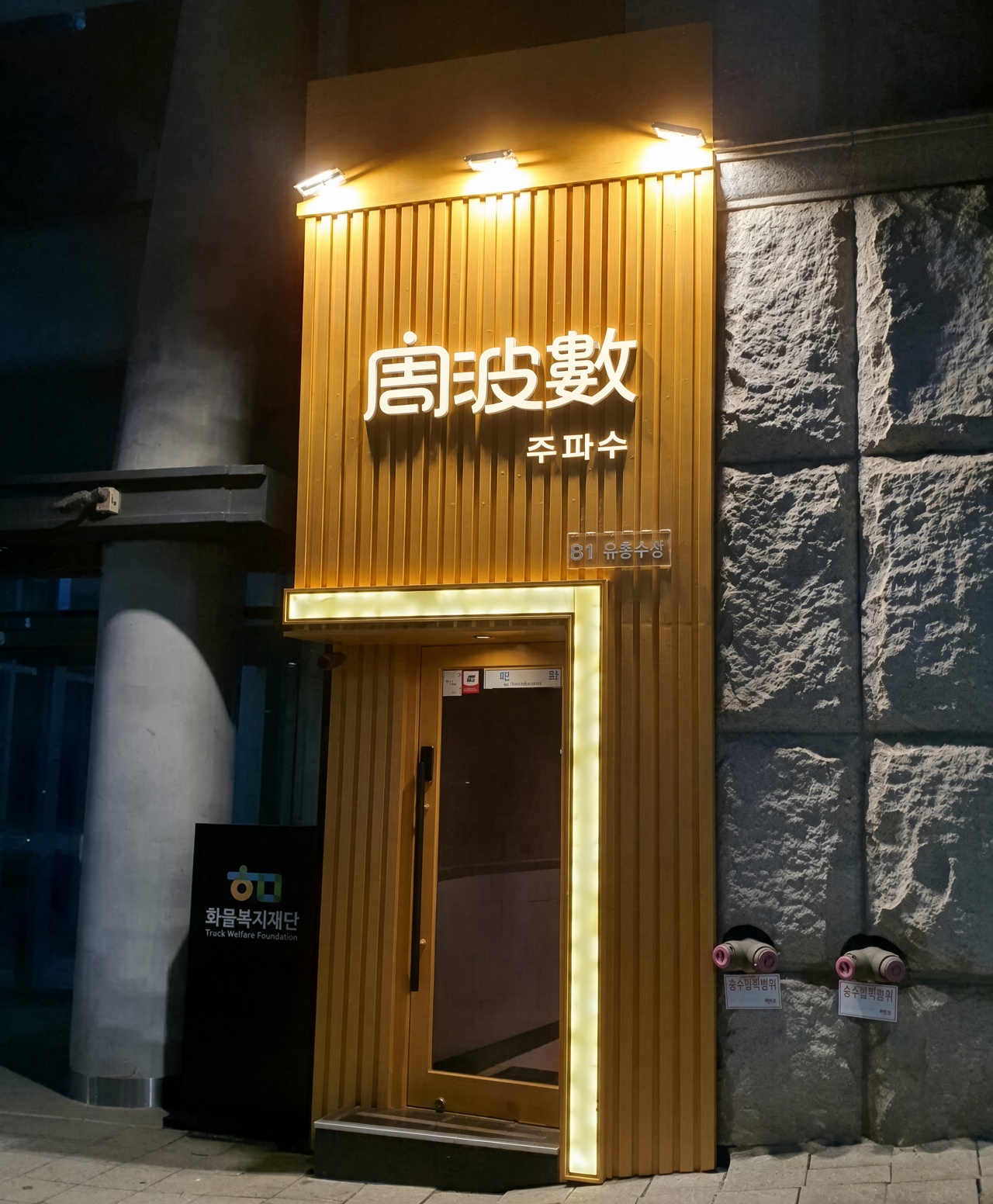 강남 주파수 · 주파수 글자와 한자가 있는 금색 세로 벽면 아래 출입문이 보입니다.