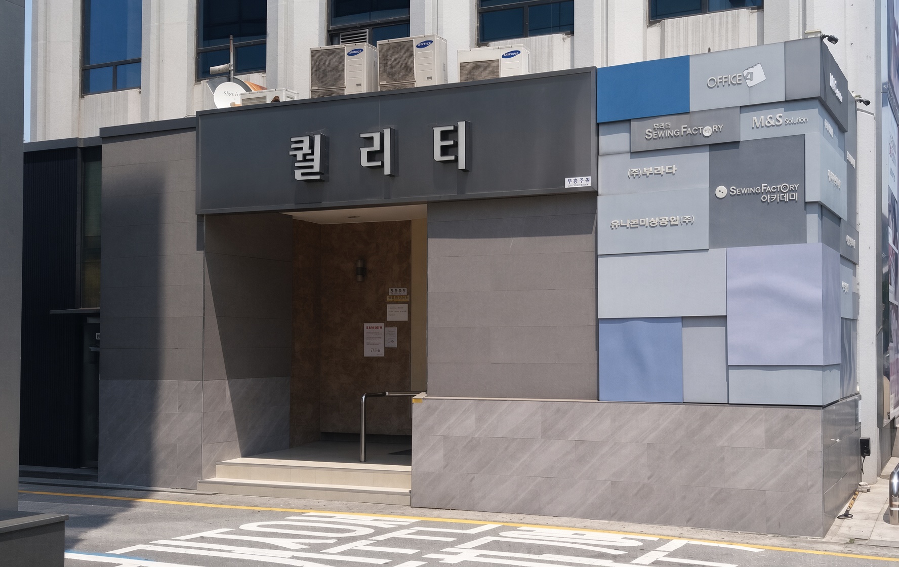 강남 퀄리티 · 퀄리티 간판 아래 회색 외벽 안으로 들어간 출입구와 앞쪽 계단이 보입니다.