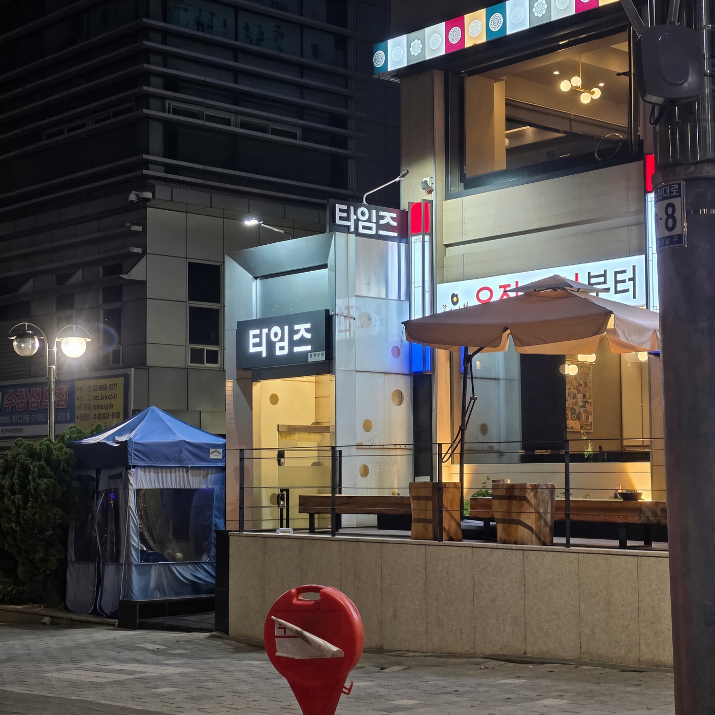 강남 타임즈 · 타임즈 간판 주변의 외부 계단과 유리 난간, 건물 앞 테라스가 보입니다.