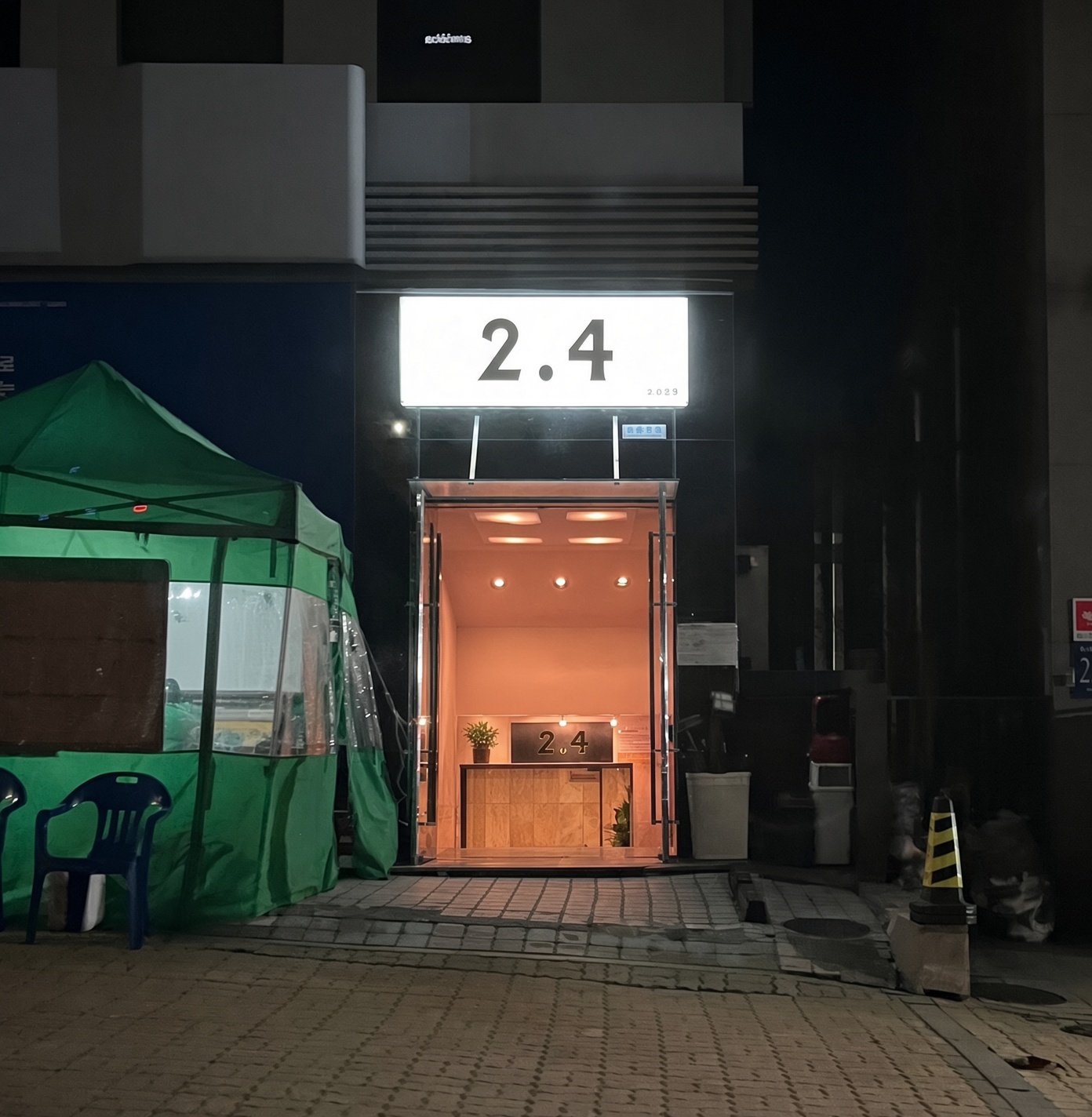 강남 2.4 · 밝은 2.4 간판 아래 유리문과 안쪽으로 내려가는 계단이 보입니다.