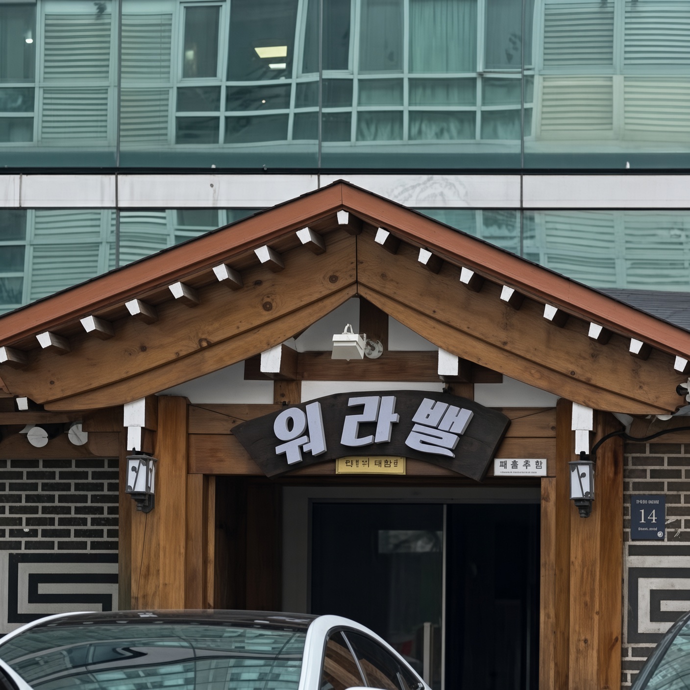 강남 워라벨 · 워라벨 간판 위 삼각형 목재 지붕과 입구 양옆 벽돌 장식이 보입니다.
