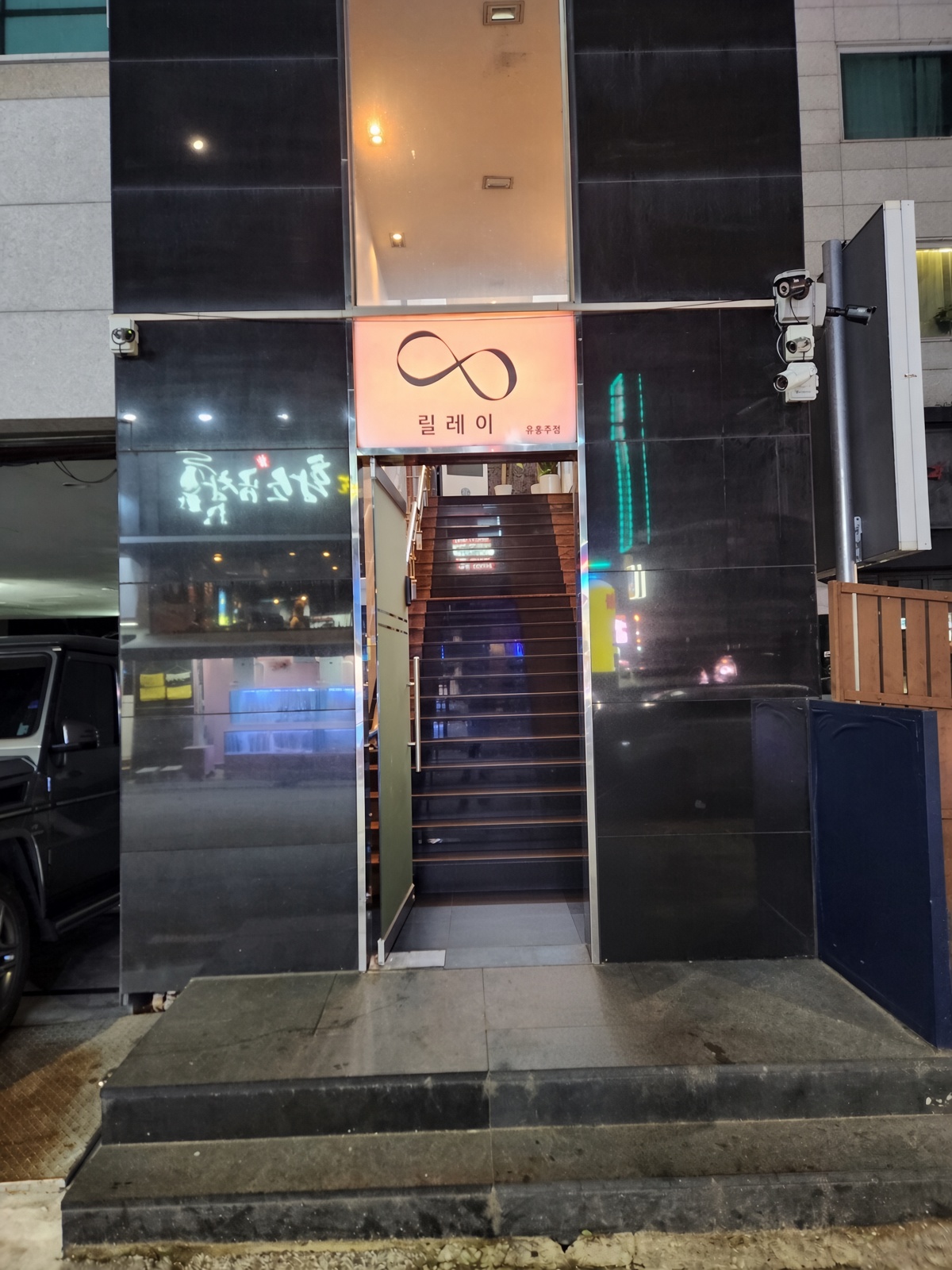 강남 제우스 · 검은 유리 외벽 사이로 간판과 위로 올라가는 좁은 계단이 보입니다.